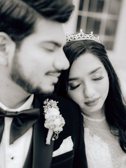 A close-up black and white portrait of the couple. The focus is on the bride's serene expression as she rests on the groom's shoulder.