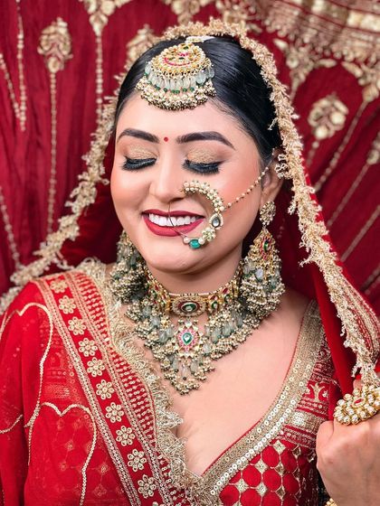 A smiling bride, her happiness radiating. This shot captures the joy and beauty of the moment, with a focus on her golden eye makeup and traditional red attire.