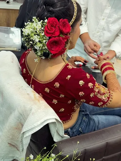 Our artist carefully applying nail polish to match the bride's outfit, while her beautiful floral bun is already complete. We take care of all the small details.