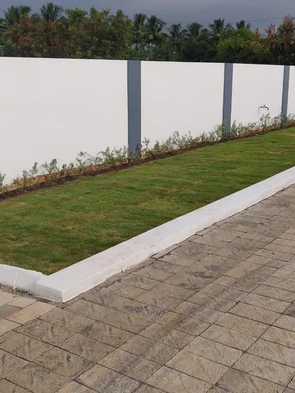 A simple yet effective design for a commercial or community space, featuring a neat strip of lawn next to a paved area, bordered by a clean white curb.