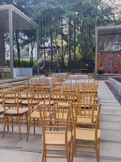 The guest seating area at the modern poolside venue, with chairs neatly arranged to face the stage. The surrounding trees and open architecture add to the sophisticated ambiance of the event.