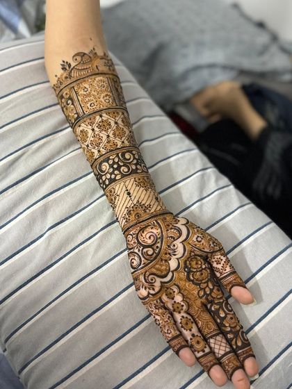 This bridal henna design features multiple bands with different patterns, creating a beautiful stacked look on the arm.