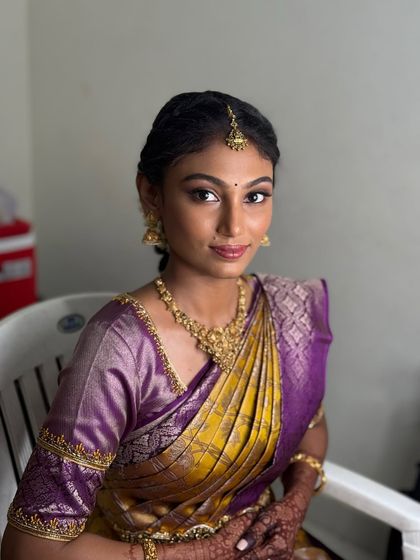 A close-up portrait of Priyanka. Her makeup is subtle yet defining, with a focus on clean skin, neat brows, and a soft lip colour.