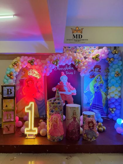 The Disney Princess stage decoration illuminated with colorful party lights, showing how the setup looks during the event. The neon signs and character backdrops create a magical atmosphere.