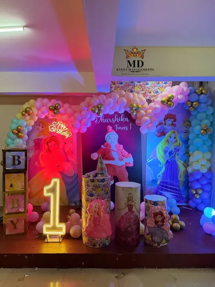 The Disney Princess stage decoration illuminated with colorful party lights, showing how the setup looks during the event. The neon signs and character backdrops create a magical atmosphere.