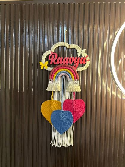 A straight-on view of the 'Raavya' nameplate, showing how all the elements come together. The off-white cloud, vibrant rainbow, and colorful hearts create a balanced composition.