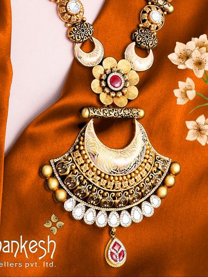 A stunning bridal pendant necklace that blends antique finish with modern design elements. The large central motif is accented with white and red stones, creating a piece of undeniable allure.