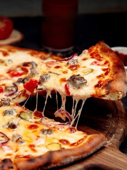 A cheesy slice of our freshly baked pizza, with that perfect cheese pull.