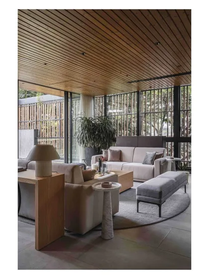 The wood-paneled ceiling adds warmth to the terrace lounge, while the floor-to-ceiling glass doors ensure a constant connection to the outdoors.