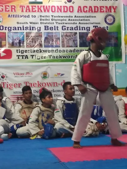 A student stands ready during a belt grading test, while others watch and wait for their turn.