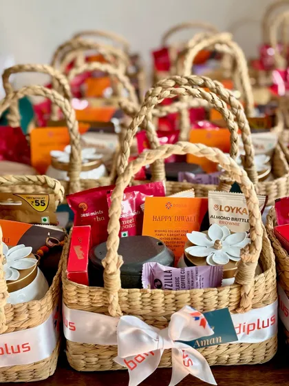 A closer look at the customized corporate Diwali hampers in cane baskets. Each basket features a custom-printed ribbon with the company's logo and a personalized name tag, adding a special touch to these employee appreciation gifts.