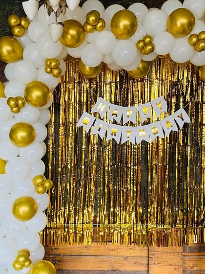A close-up of the white and gold balloon arch against a gold shimmer curtain.