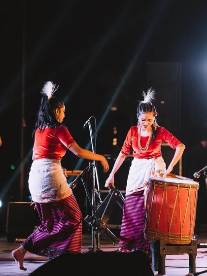 Two artists share a moment of joy while performing on the drum together. It's these candid interactions between performers that add another layer to event photography.
