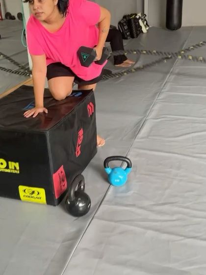 A close up of a member performing a dumbbell row on a plyo box, a great exercise for back and core.