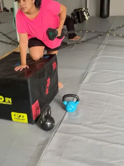 A close up of a member performing a dumbbell row on a plyo box, a great exercise for back and core.