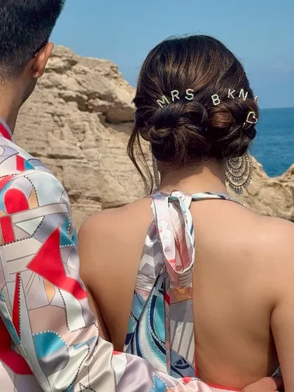 The personalized bridal bun seen from a distance, showing how it adds a unique touch to the bride's look against a beautiful ocean backdrop.
