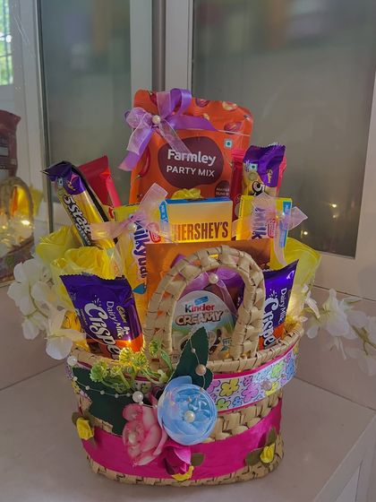 The final look of the charming yellow gift basket. It's overflowing with treats like Kinder Creamy, Hershey's, and a party mix, making it a perfect hamper for any celebration.