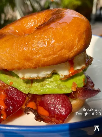 This is the Breakfast Doughnut 2.0 from our Padaria Prazeres pop-up. It's a perfect example of the playful yet delicious food I love to showcase: a maple-glazed doughnut with a fried egg, crispy bacon, avocado, and hot sauce.