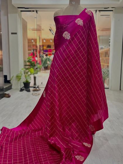 A full drape of the rani pink checks Banarasi saree on a mannequin, showing its graceful fall.