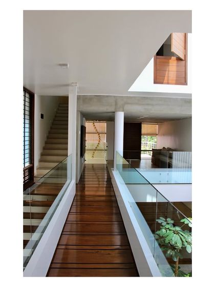 The teakwood bridge spanning the internal courtyard of the 'Boxed In House'. This element is more than a corridor; it is a viewing gallery that offers multiple perspectives of the home's different levels and the green space below, enhancing the feeling of openness.