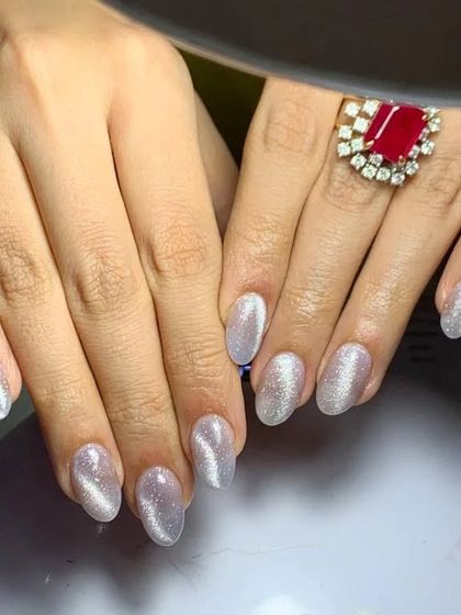 A classic silver cat eye polish on oval-shaped nails. The bright, shimmering line created by the magnetic polish gives this set a timeless and elegant feel.