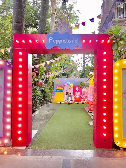 Making a grand entrance is key to setting the party mood. Here, guests are welcomed to "Peppaland" through a bright red marquee-lit archway, flanked by light-up frames featuring Peppa and George Pig, promising a fun-filled adventure from the very first step.