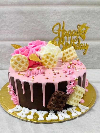 A sweet combination of chocolate and strawberry, this drip cake is topped with pink roses and white and milk chocolate waffles.