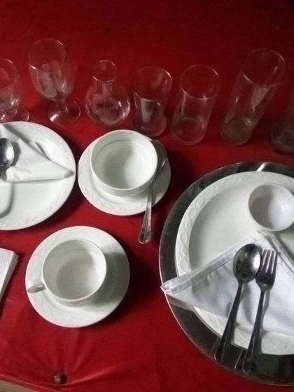 For those who prefer a modern touch, I also offer classic white porcelain crockery. This image shows a complete place setting with plates, bowls, glasses, and cutlery.