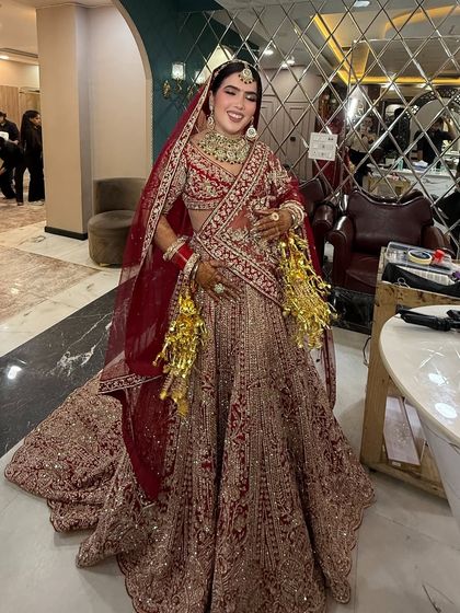 A gorgeous bride smiling brightly in her red and beige lehenga. The makeup is classic and radiant, and her happiness is the most beautiful part of the look.