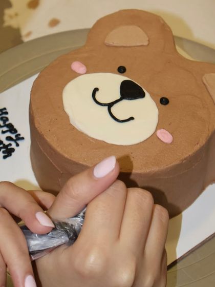 We love creating these sweet teddy bear shaped cakes. Here we are adding the final touches to a one-month celebration cake, perfect for marking those little milestones.