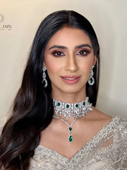 A portrait of the client, where her soft, open hairstyle highlights her stunning emerald and diamond choker.