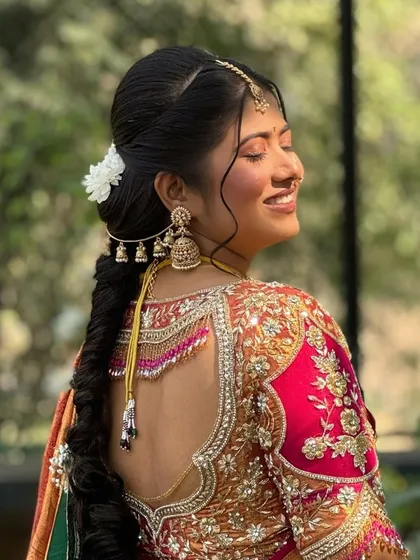 A view of the beautiful braided hairstyle adorned with flowers and a traditional parandi, completing her Maharashtrian bridal look.