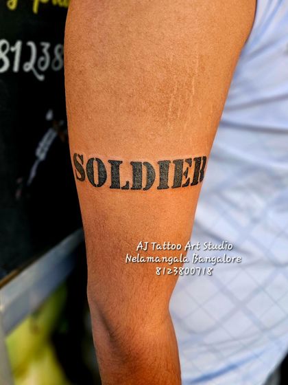 A bold "SOLDIER" armband tattoo, a powerful statement piece on the upper arm.