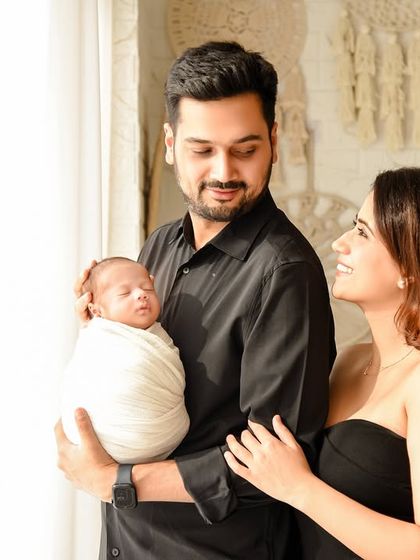 A candid moment from a newborn family session. The parents gaze lovingly at their sleeping baby, a simple and powerful image of adoration and connection.