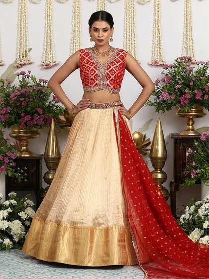A stunning combination of a beige silk lehenga with a rich, red Bandhani-inspired blouse. The contrast is both striking and elegant, perfect for a modern bride.