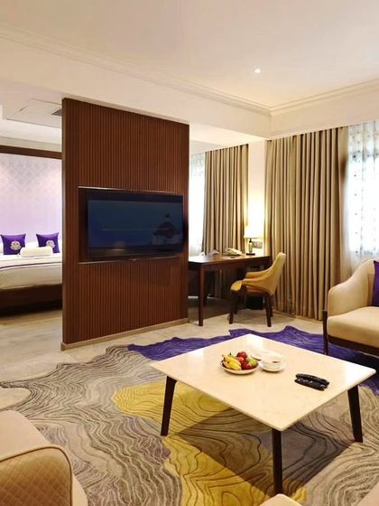 A suite at Vivanta Bengaluru, where we created a distinct separation of space using a custom media unit. The design features a rich purple and yellow color scheme in the rug and cushions, adding vibrancy to the elegant room.