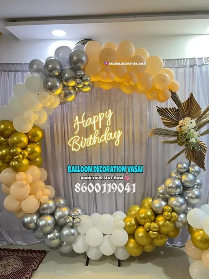 A full ring balloon arch in elegant gold, silver, and peach tones. This setup includes a floral accent and a "Happy Birthday" neon sign, creating a sophisticated photo corner.