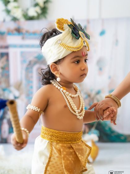 A helping hand for our little Krishna. This sweet moment shows a parent's hand guiding the baby, a reminder of the love behind every photo.