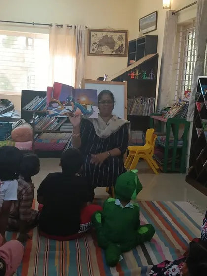 The storyteller proudly displays the book's cover, introducing the characters to the children.