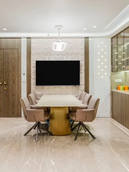 The dining area is centered around a stunning Onyx table and comfortable swivel chairs. The 3D patterned accent wall behind the TV adds depth, while the built-in crockery unit with a bar nook offers elegant storage and serving space.