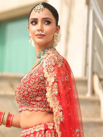 A classic pose on a staircase. The styling of this red lehenga with its long, embroidered train is perfect for creating dramatic and memorable photos.