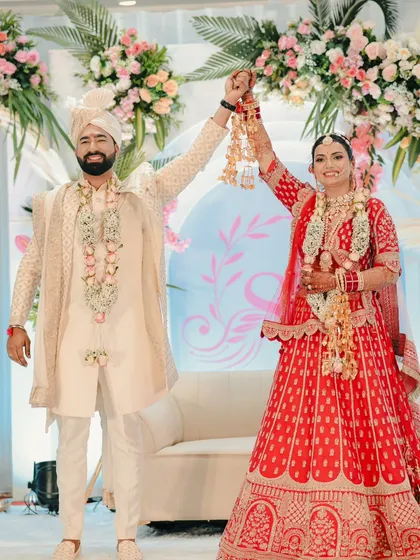 A triumphant moment on stage after the varmala ceremony, with the couple holding hands and celebrating their union.