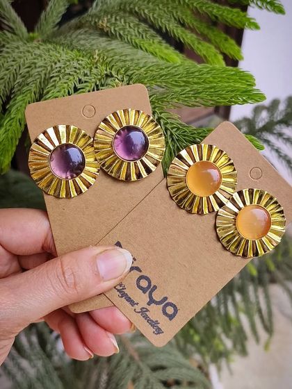 A product shot of the stunning golden brass stone earrings in both pink and yellow.