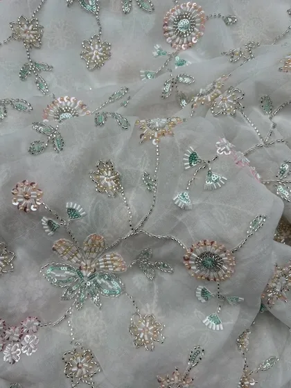 This is the kind of detail that makes an outfit unforgettable. The delicate, multi-tonal floral embroidery on this sheer georgette fabric creates a three dimensional effect, perfect for a custom wedding guest lehenga or a statement tunic.
