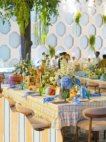The dining tables are set with yellow and blue checkered tablecloths, with centerpieces featuring characters from the Hundred Acre Wood.