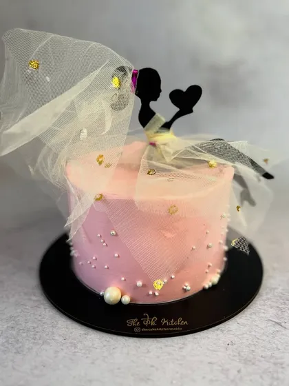 A fun and creative cake perfect for a bridal shower. This design features a silhouette topper of a bride, complete with a delicate, real tulle veil accented with gold flakes, capturing the excitement of walking down the aisle.