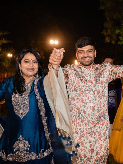 A candid shot of the brother and sister dancing. His printed kurta adds a touch of modern flair to a traditional silhouette, reflecting his personal style.
