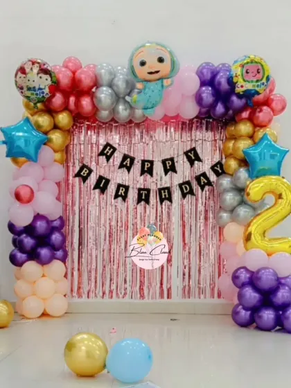 A Cocomelon themed birthday backdrop with a balloon frame, shimmer curtain, and character foil balloons for a second birthday.