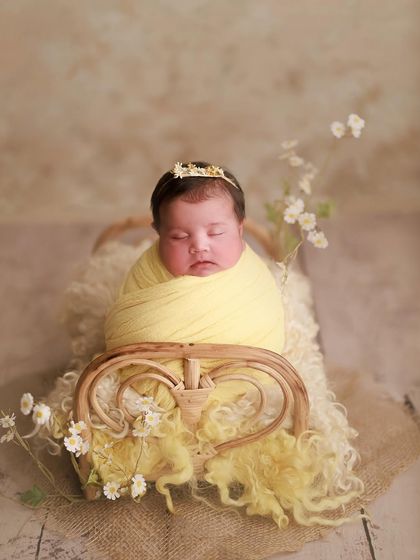 Innocence in yellow. This little one is wrapped in a sunny yellow swaddle, resting on a tiny bed surrounded by delicate white flowers.