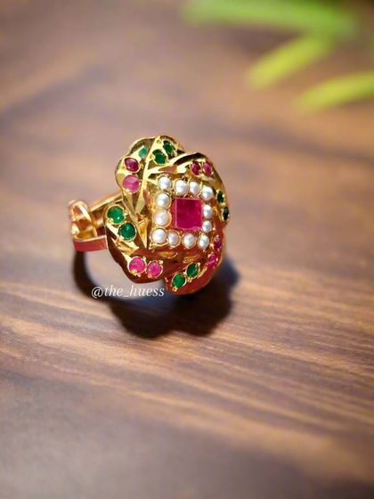 The 'Sia' adjustable ring, beautifully photographed on a wooden surface. This ring features a square central stone with multi-coloured accents.